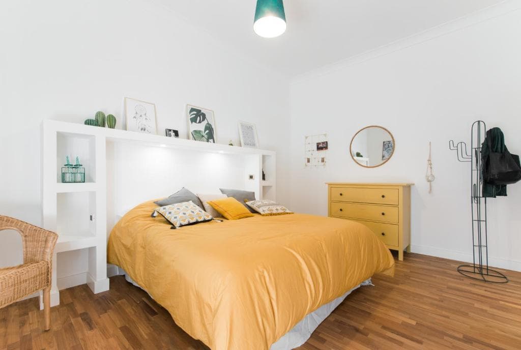 Bedroom with double bed, yellow chest of drawers and wooden floor